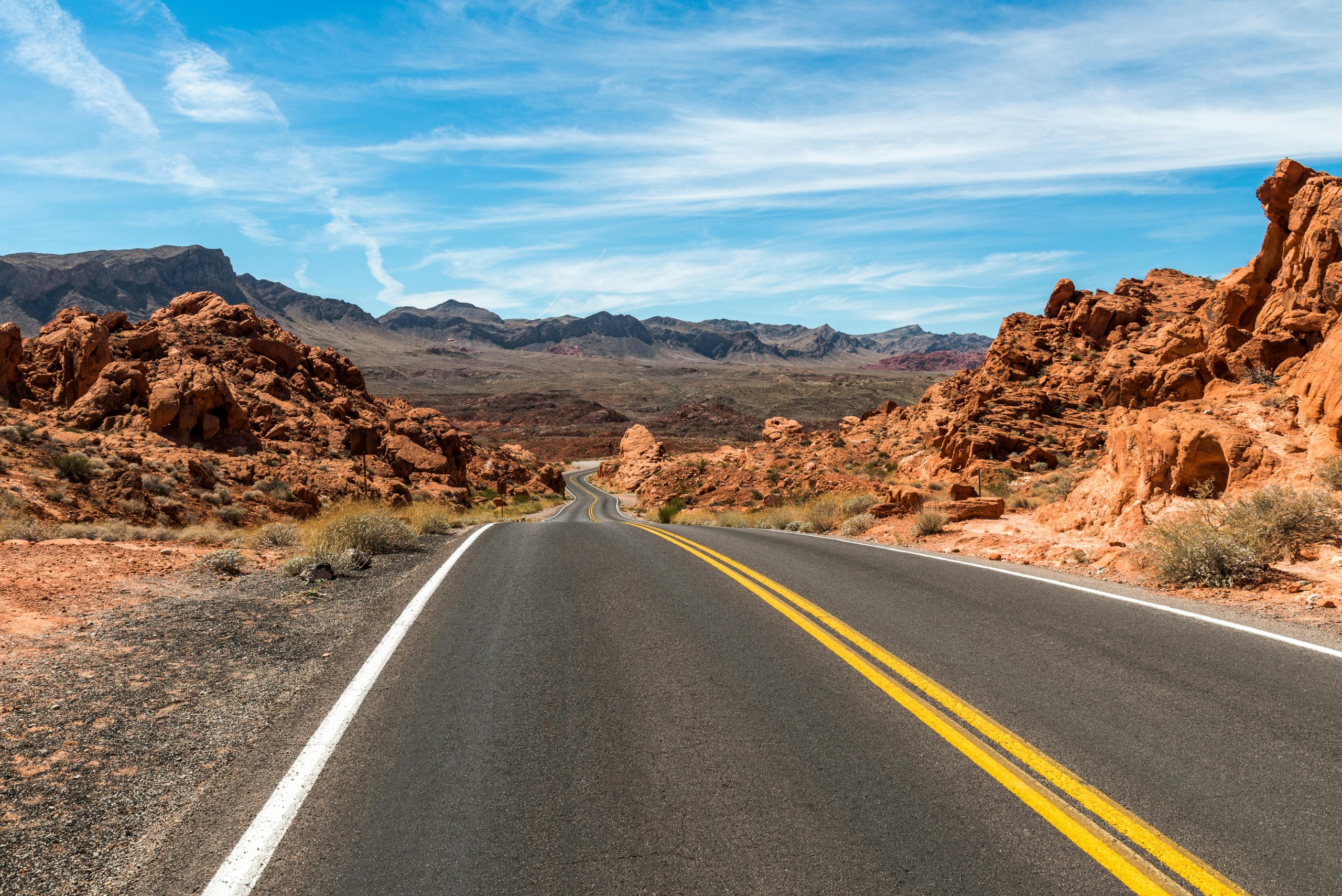 A winding road through a stunning desert landscape with blue skies and rocky formations.